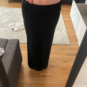 Svart långkjol från Gina Tricot - Snygg svart långkjol från Gina Tricot. Perfekt för olika tillfällen och lätt att matcha med olika toppar. Kjolen har en  bra passform och är tillverkad i ett bekvämt material.