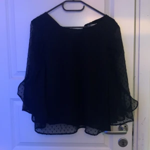 Svart blus med prickigt mönster - Snygg svart blus med ett diskret prickigt mönster från H&M. Blusen har långa, fladdriga ärmar och en luftig passform. Perfekt för en stilren look.