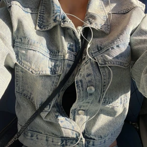 Jeansjacka i kroppadstil - Snygg jeansjacka i ljus denim med klassisk krage och knappar framtill. Jackan har en avslappnad passform och långa ärmar. Den är M men passar S jättebra.