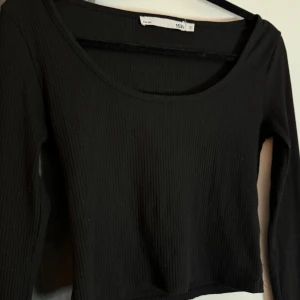 Svart ribbad topp - !LÄS BIO INNAN KÖP! Säljer denna långärmade toppen med ribbat material. Är en liten defekt på sidan - en eller två trådar. Om fler bilder önskas är det bara att höra av sig!