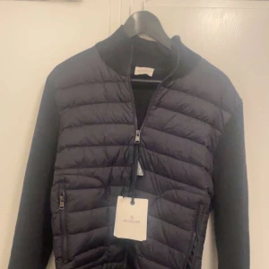 Navy blue Moncler cardigan  - Säljer nu en navy blue Moncler cardigan i storlek M. Jackan är i oanvänt skick och är helt ny.