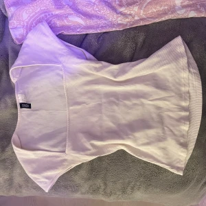 Vit topp - Säljer en stilren vit ribbad topp från HM. Toppen har en fyrkantig halsringning och korta ärmar, perfekt för en avslappnad look. Passar bra till både jeans och kjol. Hör av dig vid intresse!