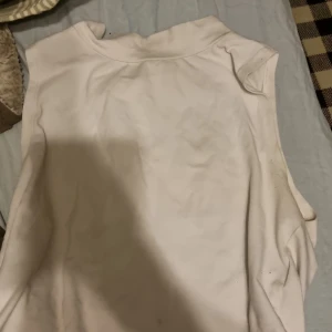 Vit ärmlös topp från Gina Tricot - Säljer en enkel och stilren vit ärmlös topp från Gina Tricot. Perfekt för varma dagar eller som ett basplagg i garderoben. Toppen har en rund halsringning och är gjord i ett mjukt material.