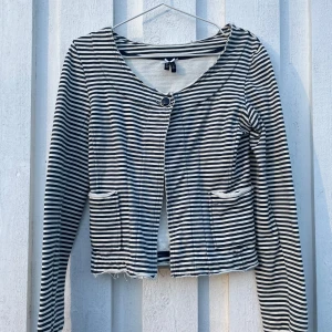 Randig kofta med knappar - Säljer en stilren randig kofta med knappar framtill. Koftan har en v-ringad design och långa ärmar. Perfekt för lager-på-lager-stil. Måste tyvärr sälja då den är lite för liten för mig🫶🏼