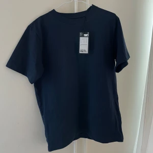 Mörkblå t-shirt från Weekday - Säljer en stilren mörkblå t-shirt från Weekday. Den har en boxig passform och är tillverkad i ett kraftigare bomullsmaterial. Perfekt för en avslappnad look. Helt ny