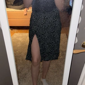 Svart blommig kjol från Shein - Snygg svart kjol från Shein med vita blommor och en slits i storlek S