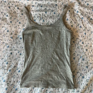 Grå ribbad linnetopp från Gina Tricot - Säljer en stilren grå ribbad linnetopp från Basically Basics Gina Tricot. Perfekt för lager-på-lager eller att bära som den är. Toppen har en enkel och klassisk design med smala axelband. Har kommit till användning fåtal gånger!