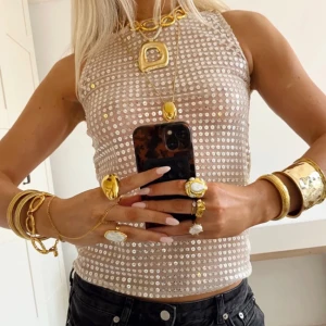 Glittrig ärmlös topp - Snygg glittrig ärmlös topp i guld med paljetter. Trendig och passar perfekt till festliga tillfällen! Helt oanvänd och förpackningen är inte ens öppnad. Fick två i present!😅