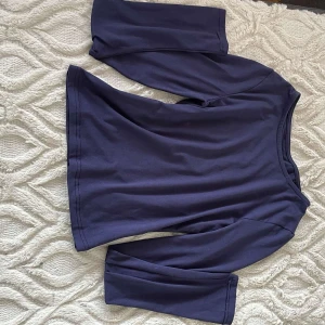 Mörkblå långärmad topp - Säljer en stilren mörkblå långärmad topp i mjukt material. Perfekt för en lite kyligare sommarkväll. Lite kortare vid magen. 