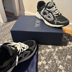 Svarta sneakers från Dior - Snygga svarta sneakers från Dior med vita detaljer och snörning. Skorna har en modern design med en bekväm sula och är perfekta för en stilren look.