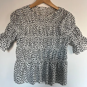 Prickig topp - Säljer en söt prickig blus från Zara. Blusen har en luftig passform och är perfekt för både vardag och fest. Den är tillverkad i ett lätt och bekvämt material. Storlek S