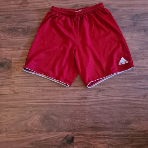 Röda shorts från Adidas - Snygga röda shorts från Adidas med vit logga på benet. Perfekta för träning.