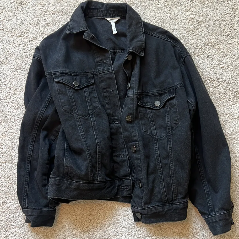 Säljer en snygg svart jeansjacka från Object i storlek XS. Jackan har en klassisk design med knappar framtill och två bröstfickor. Perfekt för en cool och avslappnad stil. 🖤. Takit.