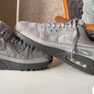 Grå Nike Air Max sneakers - Snygga grå Nike Air Max sneakers med klassisk design och synlig luftdämpning i sulan. Skorna har snörning och en rund tå, vilket ger en bekväm passform. Perfekta för både vardag och träning.