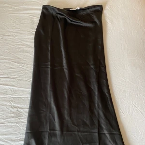 Svart långkjol i satin - Elegant svart långkjol i satin, varsamt använd. Två små fläckar där fram, men annars i fint skick!