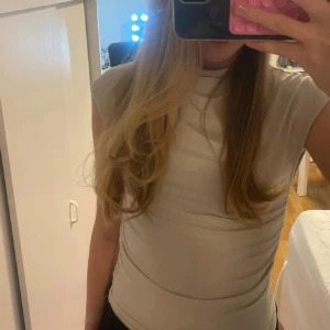 Vit linnetopp från Gina Tricot - Säljer en beige tröja från Gina Tricot som är ribbad på sidorna. Använd ett par fåtal gånger 