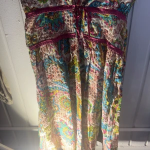 Mönstrad klänning från Charfal - Säljer en färgglad klänning från Charfal i storlek S. Klänningen har ett livfullt mönster i blått, rosa, gult och grönt med inslag av brunt. Den har en normal passform och är perfekt för sommarens varma dagar.