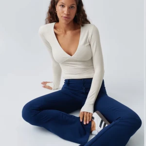 Beige långärmad topp från Gina Tricot  - Säljer en vit beige aktig långärmad topp från gina tricot med v-ringning. Toppen har en tight passform och är i storlek XS. Materialet är mjukt och stretchigt för extra komfort. Säljer pga att plagget ej kommer till användning. ❣️