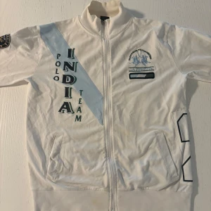 Vit jacka från La Martina - Säljer en vit jacka från La Martina med dragkedja och broderade detaljer. Jackan har långa ärmar och en hög krage. Perfekt för dig som gillar stilrena och sportiga plagg. 🏇