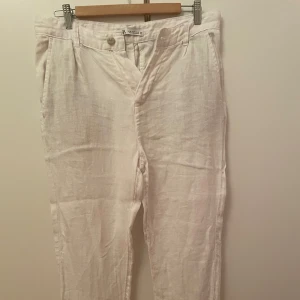 Linnebyxor  - Säljer ett par helt nya vita linnebyxor från Zara. Byxorna har en avslappnad passform och är perfekta för varma dagar. De har en klassisk design med dragkedja och knapp framtill. 