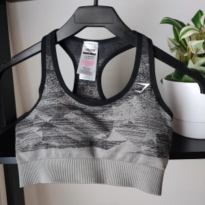 Mönstrad sportbh från Gymshark i storlek S - En svart mönstrad sportbh från märket Gymshark. Storlek S. Stretchig i materialet. Intakt logga. Helt ny utan lapp. Det finns inlägg i bhn men dom går att ta ut om man föredrar det. Resår i nederkant. Går att matcha med de mesta.