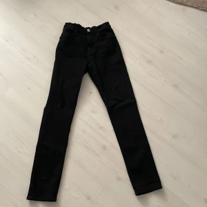 Svarta skinny jeans från &Denim - Säljer ett par svarta skinny jeans från &Denim. De har en klassisk design med knapp och dragkedja framtill. Perfekta för en stilren look.