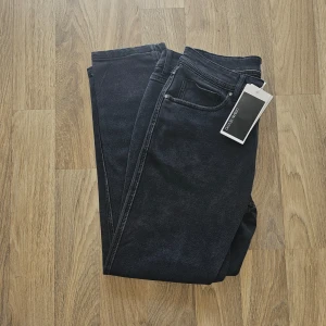 Svarta jeans från Urban Revivo - Snygga svarta jeans från Urban Revivo med klassisk femficksdesign. De har en normal passform och är perfekta för en stilren look. Jeansen har en midwaist och är tillverkade i ett slitstarkt material.