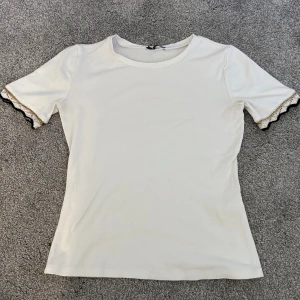 Vit kortärmad topp från Zara - Säljer en stilren vit topp från Zara med korta ärmar. Ärmsluten har en fin spetsdetalj och tröjan är i storlek M. Använd fåtal gånger och ser ny ut💗