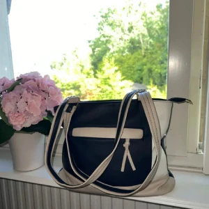 Blå och beige axelväska - Snygg blå axelväska med beige detaljer och dragkedja. Väskan har flera fack både inuti och utanpå samt är rymlig! Använd enstaka gång