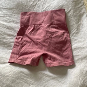 Rosa tränings shorts - Säljer ett par rosa shorts med hög midja. De är tillverkade i ett stretchigt material och har en tight passform. Perfekta för träning eller en avslappnad dag. 💖jag är inte helt säker men jag tror att dem är oanvända, köpte dem för länge sen men glömde bort att dem fanns och nu har jag ett par liknande