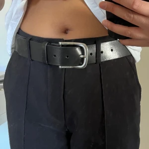 Svart bälte från Marc O'Polo - Snyggt svart bälte i skinn från Marc O'Polo med ett stilrent silverfärgat spänne. Bältet har en enkel design med justerbara hål för bästa passform. Aldrig använt utan bara testat det men ingen prislapp kvar tyvärr. Är 4 cm brett och det står 80 som storlek på skärpet. Gjort av läder.