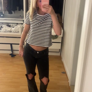 Svartvit randig t-shirt - Säljer en svartvit randig t-shirt med kort ärm och avslappnad passform. Perfekt till jeans eller shorts för en enkel och stilren look. T-shirten är croppad och har rund halsringning.