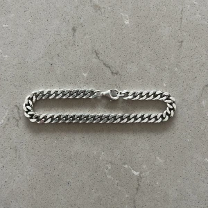 Kedjearmband, 17,5 cm lång 5 mm bred - Stilrent armband med kraftig kedja i silverfärg. Klassisk design med karbinhake som lås. Passar perfekt för dig som gillar en enkel men ändå tuff accessoar. Köpt för 1100kr. Använd en gång!