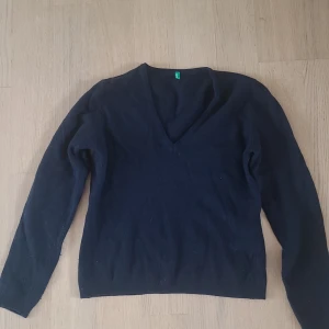 Svart v-ringad tröja från Benetton - En svart långärmad tröja från Benetton med v-ringning. Enkel och stilren modell som passar perfekt till många olika outfits. Mjuk och skön, perfekt för kyligare dagar.