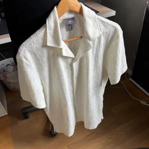 Vit skjorta från H&M - Stilren vit kortärmad skjorta från H&M i nyskick. Storlek S men sitter bättre som en M. Perfekt för en somrig och fräsch look!
