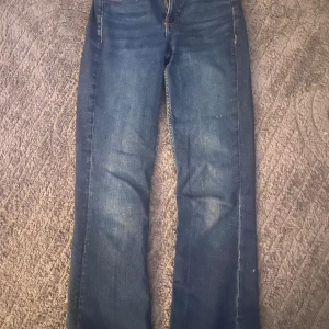 Blå jeansbyxor från Denim - Klassiska blå jeansbyxor från Denim kappahl med raka ben och normal passform. Byxorna har fem fickor och stängs med dragkedja och knapp. Perfekta till vardags och enkla att matcha med olika toppar.