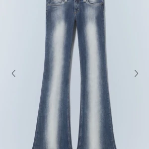 Blå bootcut low waist jeans med slitningar - Säljer ett par blå bootcut jeans med ljusa slitningar framtill och baktill. Jeansen har låg midja och klassisk femficksdesign. Perfekta för dig som gillar en retroinspirerad look med utsvängda ben. Storleken är W29 L34 men har sytt upp dom så passar mer som en L32