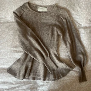 Beige ribbad stickad tröja från Studio - Supersnygg beige stickad tröja från Studio med ribbad struktur och markerad midja. Tröjan har långa ärmar och en rund halsringning. Perfekt för lager-på-lager och enkel att styla till olika outfits.