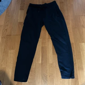 Mörkblåa mjukisbyxor från Dressmann - Mörkblåa mjukisbyxor från Dressmann med dragsko i midjan och två sidofickor. Perfekta för en avslappnad stil och bekväma dagar. Byxorna har en enkel och stilren design utan synliga loggor eller mönster.