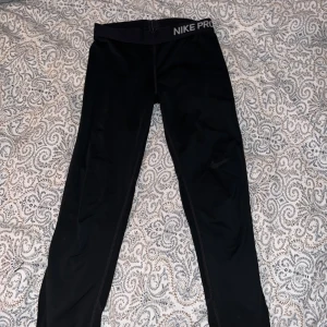 Svarta träningstights från Nike Pro - Svarta tights från Nike Pro med elastisk midja och diskret logga framtill. Perfekta för träning eller sportaktiviteter. 