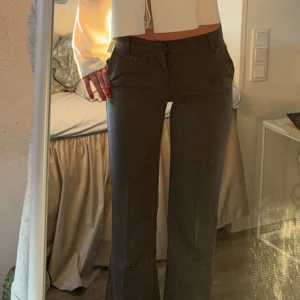 grå lågmidjade kostymbyxor - Snygga gråa kostymbyxor med bootcut passform och låg midja. Byxorna har klassisk design med knäppning och dragkedja framtill. Använda ett fåtal gånger då de tyvärr är för korta. 💕 Jag är 170