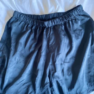Mörkgrå shorts från Softer Days - Mörkgrå shorts från Softer Days med elastisk midja och avslappnad passform. Perfekta för varma dagar eller som mysplagg hemma. Lätta och mjuka i materialet för extra komfort.