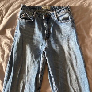 Ljusblå raka jeans - Säljer ett par klassiska ljusblå jeans med raka ben och hög midja. Jeansen har fem fickor, knappgylf och är i ett tidlöst denimtyg. Perfekta för en avslappnad och stilren look. ca 70 cm lång i benen
