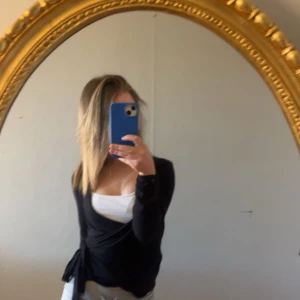 Svart omlottopp med knyt - Säljer en svart omlottopp med långa ärmar och knyt i sidan från lager 157.