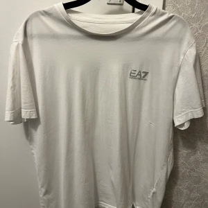  t-shirt EA7  - Vit t-shirt från EA7 Emporio Armani med diskret logga på bröstet. Klassisk rund halsringning och korta ärmar. Tillverkad i mjuk bomull som känns skön mot huden. Perfekt för en clean och stilren look.