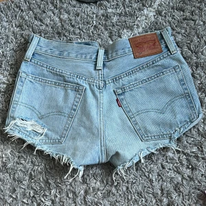 Levi's 501 ljusblå jeansshorts - Ljusblå jeansshorts från Levi's modell 501 med  fransade kanter och slitningar. Jag säljer dessa pågrund av att de tyvärr är försmå för mig! De är i gott skick och super snygga 