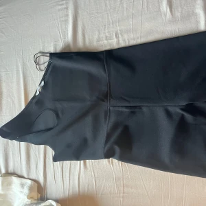 Svart kort jumpsuit H&M - Säljer en svart, ärmlös och tight jumpsuit från H&M. Jumpsuiten har en enkel och stilren design med rund halsringning och kort längd. Perfekt för dig som gillar minimalistisk stil.
