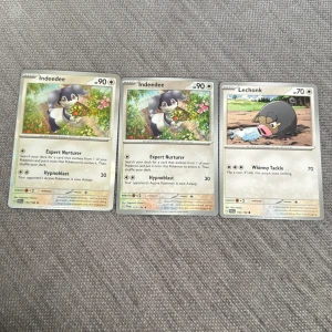 Pokémonkort: Indeedee och Lechonk - Tre Pokémonkort säljes: två med Indeedee och ett med Lechonk. Korten har färgglada illustrationer och klassisk Pokémon-design med namn, HP och attacker. Perfekt för samlare eller spelare som vill utöka sin samling.