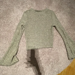 Grå ribbad croppad tröja från SHEIN - Säljer en grå ribbad croppad tröja från SHEIN med långa trumpetärmar. Tröjan är mjuk och stretchig, perfekt till jeans eller kjol. Materialet är en mix av polyester, rayon och elastan.