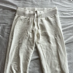 Vita mjukisbyxor från Nelly - Supermjuka vita mjukisbyxor från Nelly med bred ribbad midja och dragsko. Perfekta för en avslappnad stil och sköna att ha på sig hemma. Byxorna har en enkel och stilren design utan synliga detaljer. Dom är lågmidjade och ganska tight runt bena. Säljer dessa byxor eftersom de är för små för mig ! Inga synliga fläckar eller hål. 